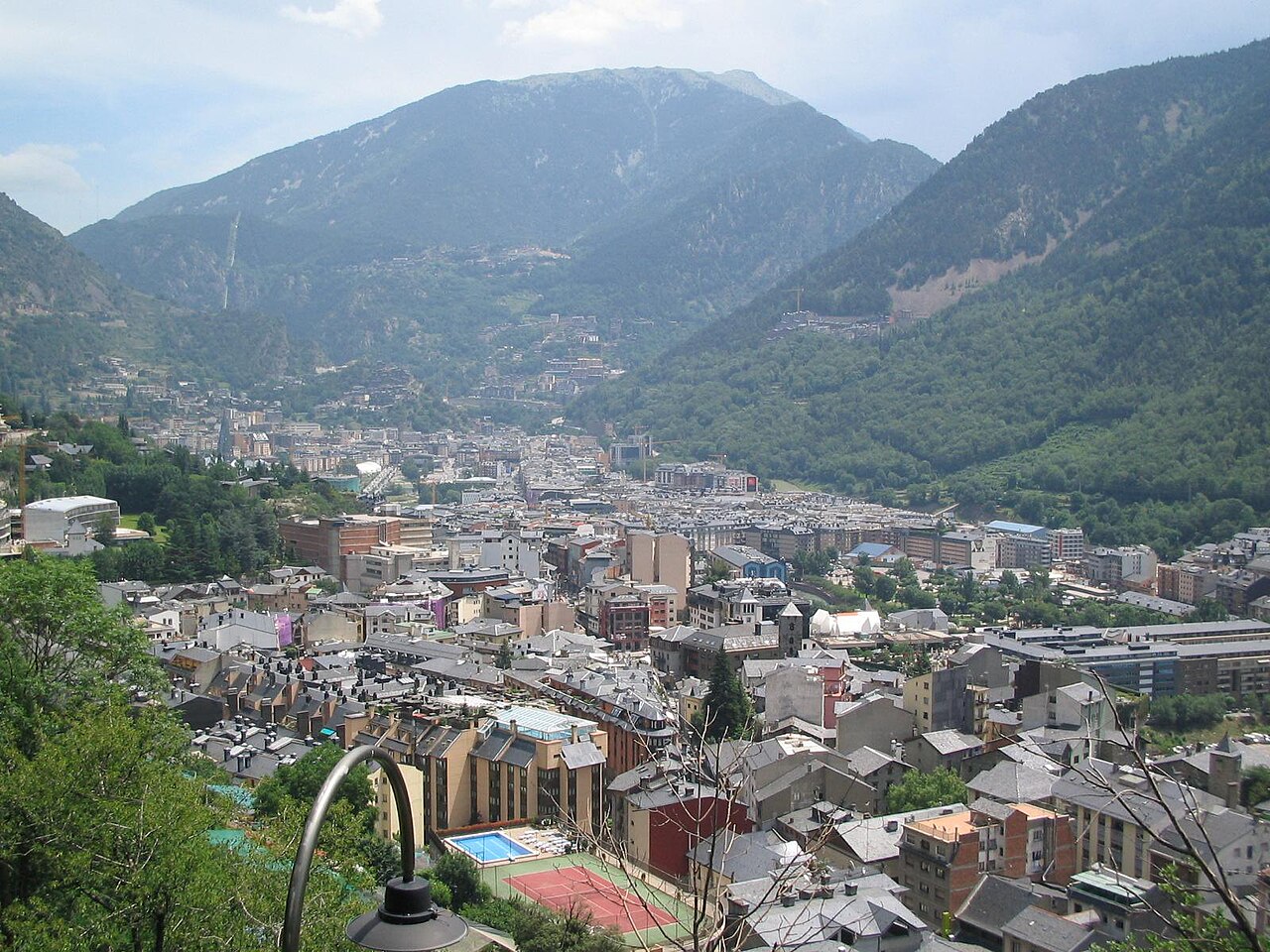 Vista de Andorra la Vella y el valle central rodeados de montañas verdes en un día soleado
