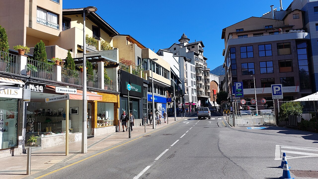 Calle comercial de Andorra la Vella con tiendas y edificios en un día soleado